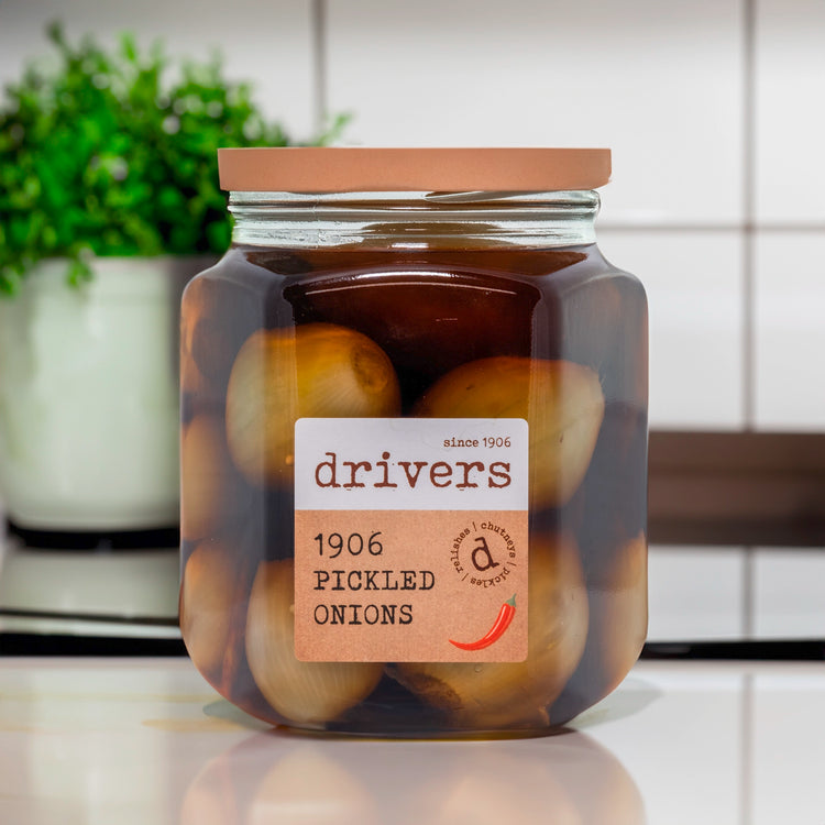 A hexagon glass jar with a label with the drivers logo. This image is in a lifestyle setting with a white kitchen in the background