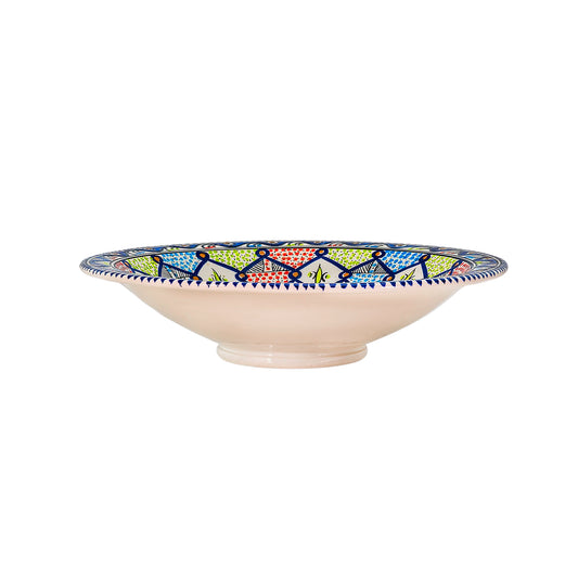 A deep extra large Moroccan style ceramic bowl from the side with intricate starburst patterns in vibrant colors of blue, green, red, and white