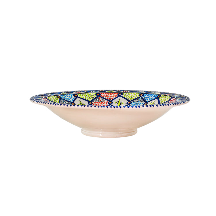 A deep extra large Moroccan style ceramic bowl from the side with intricate starburst patterns in vibrant colors of blue, green, red, and white