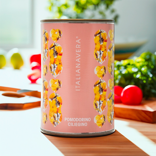 Itailanavera logo on a pink tin with yellow botanical flowers. The tin is in a kitchen setting with tomatoes blurred in the distance