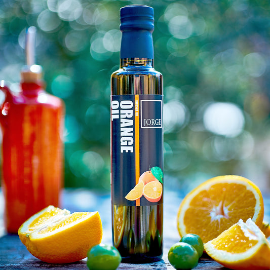 The glass bottle of Orange oil. In the image the Orange oil bottle is on a table with Oranges resting on the bottle.