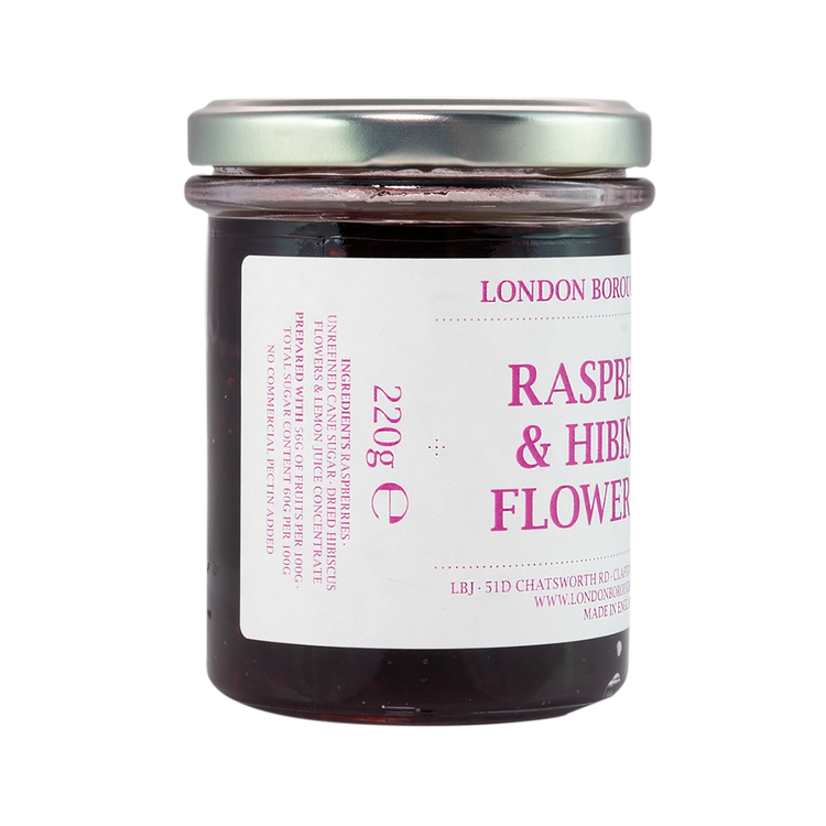 Glass jar of London Borough of Jam Raspberry & Hibiscus Flower Jam. The jar is filled with a deep red jam and has a silver lid. The label is white with purple text, listing ingredients, weight, and contact information.
