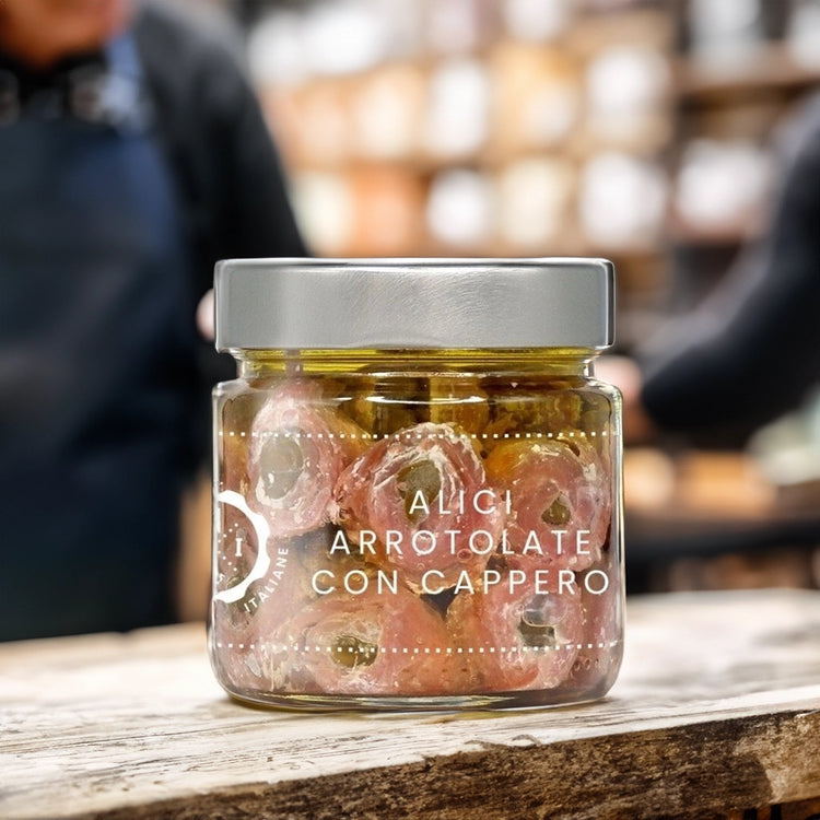 Jar of Rolled Anchovies stuffed with Capers on wooden table in artisan shop