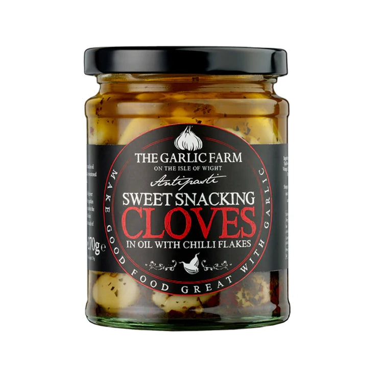 A glass jar with a black label, on the label is the garlic farm logo with the title of sweet snacking cloves in oil with chilli flakes in bold.