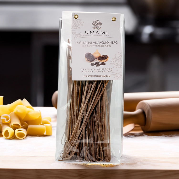 See through packet of pasta on a wooden table, surrounded by pasta and rolling pins