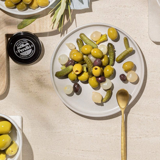 Perelló olives and pickles on a table with plate and wooden soon