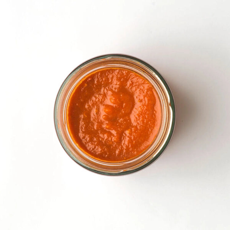 A small glass jar filled with a thick, red nduja sauce