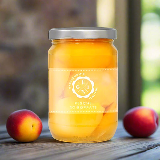 Jar of peaches on table with 2 peaches sat next to it