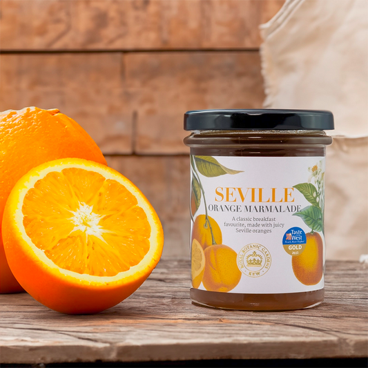 Kew gardens seville orange marmalade on a wooden table next to an orange 